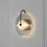 Modern wall lamp with minimalist Nordic design illuminating a cozy bedroom bedside