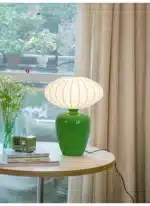 Vintage table lamp with retro ceramic base and silk shade on bedside table in cozy bedroom