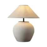 Wabi sabi table lamp with textured ceramic base and linen shade in a cozy living room