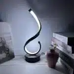 Modern desk lamp with adjustable arm and USB cable, glowing warmly on a wooden desk