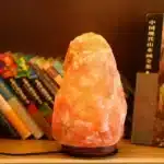 Salt lamp with color changing on wooden base glowing in warm light