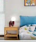 Modern glass table lamp with spherical shade on a wooden nightstand in a cozy bedroom