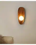Vintage wall sconce with wooden backplate and clear glass shade, warm light