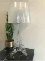 Modern acrylic table lamp glowing softly on a bedside table in a contemporary bedroom