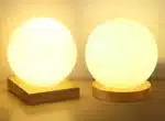 Modern table lamp with iron body and wood base illuminating a cozy bedroom