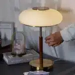 White glass table lamp with vintage design on a wooden desk in a cozy bedroom