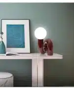 Modern glass table lamp with spherical shade on a wooden nightstand in a cozy bedroom