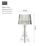 White ghost table lamp with transparent baroque design on a bedside table in a modern bedroom
