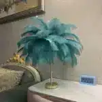 Ostrich feather table lamp glowing warmly on a bedside table in a cozy bedroom