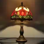 Tiffany table lamp with tulip stained glass shade, rustic bronze base, glowing warmly