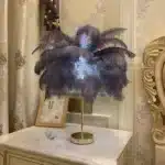 Ostrich feather table lamp glowing warmly on a bedside table in a cozy bedroom