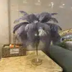 Ostrich feather table lamp glowing warmly on a bedside table in a cozy bedroom