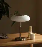 White glass table lamp with vintage design on a wooden desk in a cozy bedroom