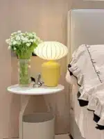Vintage table lamp with retro ceramic base and silk shade on bedside table in cozy bedroom