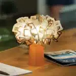 Modern table lamp with PVC flower design in a cozy bedroom setting