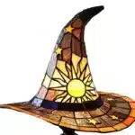 Witch hat lamp with stained glass pattern casting a warm glow on a bedside table