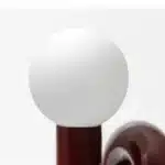 Modern glass table lamp with spherical shade on a wooden nightstand in a cozy bedroom